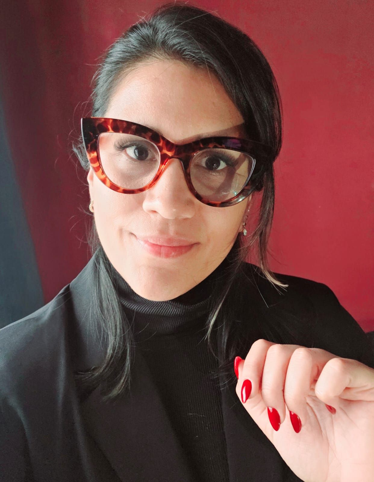 Carla Lopez, abogada, con anteojos de marco carey y saco negro, sonriendo a cámara